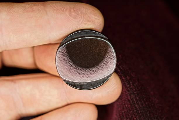 istock fingers on the hand hold one large plastic brown purple button 1359842651
