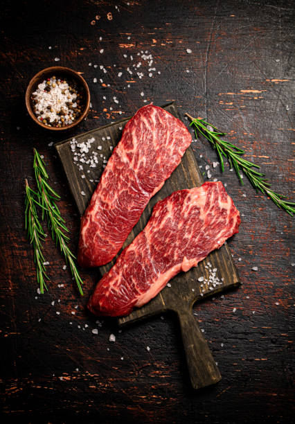 istock Raw steak on a wooden cutting board with spices. 1359843054
