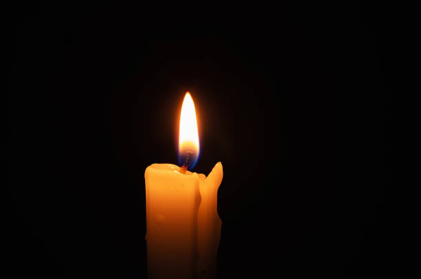 Burning candle in total darkness stock photo