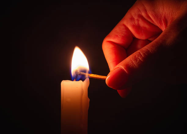 fiammifero di legno acceso che accende una candela nell'oscurità. - arson black bright burning foto e immagini stock