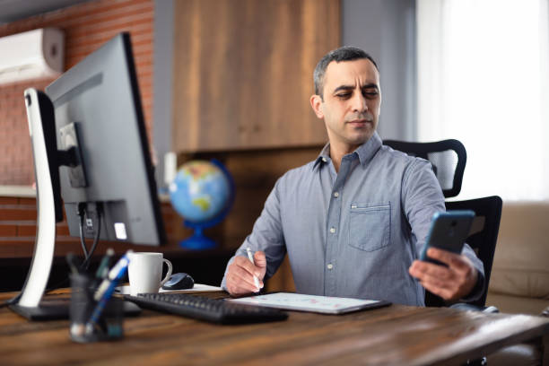 cansado empresario en la oficina tiene dificultades para ver textos en su teléfono inteligente, concepto para el comienzo de la presbicia justo después de la edad de 40 años. - beginning of life fotografías e imágenes de stock