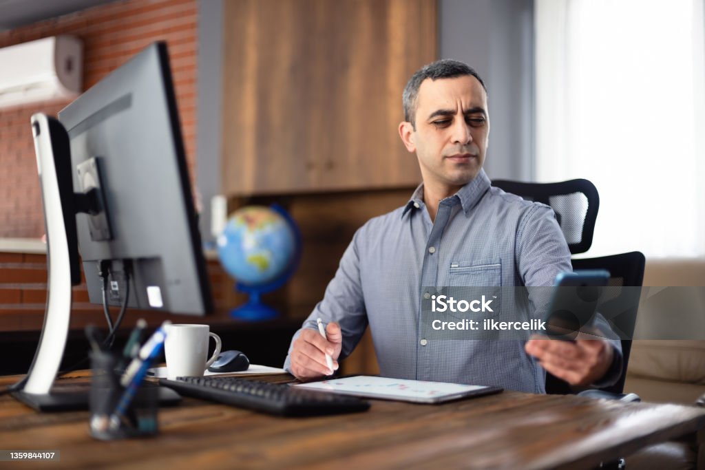 Tired Businessman In The Office Has Difficulty To See Texts On His Smartphone, Concept For The Beginning Of Presbyopia Just After The Age Of 40 Years. Presbyopia Stock Photo