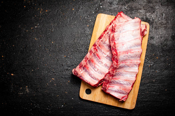 côtes levées crues sur une planche à découper. - porc viande photos et images de collection