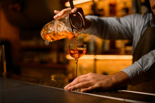istock view of mixing cup with cold cocktail and strainer from which the beverage is poured into a wine glass 1359846893