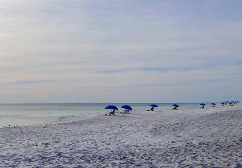 Empty Seagrove Beach with blue umbrellas and loungers on a hazy winter day. Seaside, Florida - USA