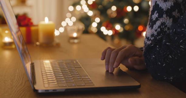 istock Close-up hand enter gift card on web page sending Merry Xmas eve wishing text on e-mail working on digital tablet laptop at home. Good warm time cozy night winter season with tree light inside house. 1359848524