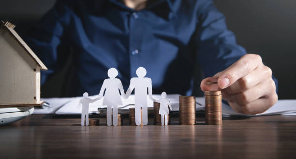 istock Man with a paper family and stack of coins. 1359850848