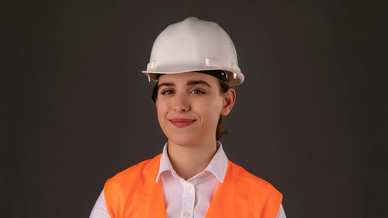 Business woman in orange business suit over white shirt. Beautiful engineer woman smiling looking at camera. He works in the construction or industrial sector. The woman was alone in front of the camera. With a smiling facial expression.