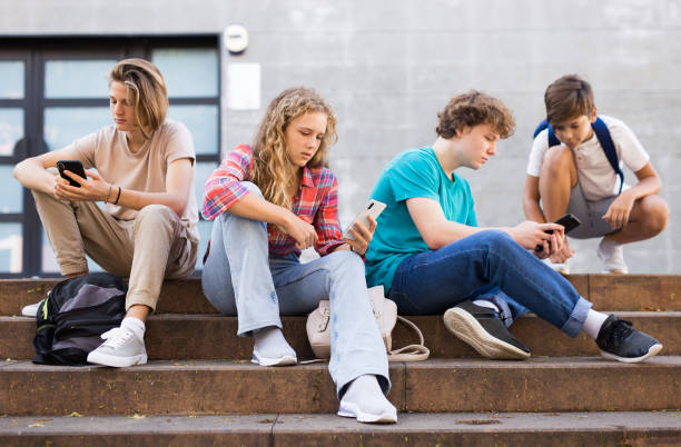 istock Teens with smartphones on stairs beside shool building 1359855938