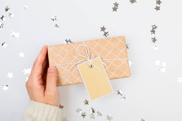 istock gifts or presents boxes silver confetti on white table top view. female hands in a warm sweater are holding a gift 1359856348
