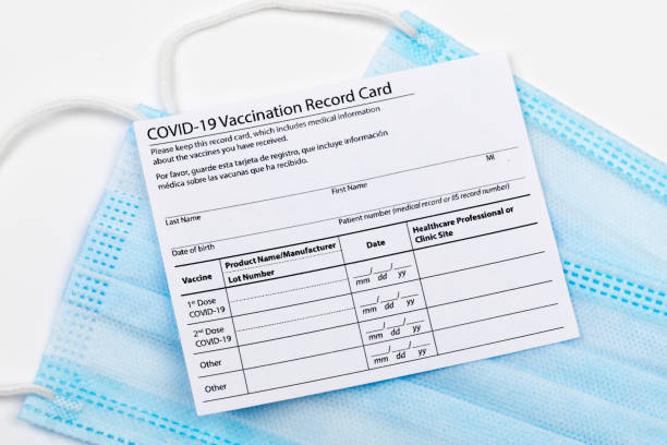 istock Coronavirus vaccination record card. Protective mask divided into two parts. Concept of defeating Covid-19 1359856365