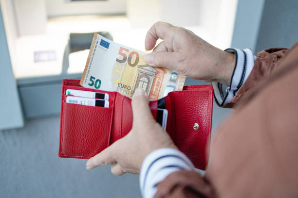 Unrecognizable female holding in hands wallet with euro money near the ATM. Withdrawing cash to pay for services, a loan or study ATM machine and euros cash. Closeup of woman hand holding euro banknotes. Withdraw money from an ATM european union euro note stock pictures, royalty-free photos & images