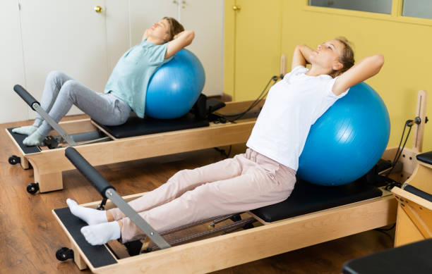 gym fille pilates sports d’étirement dans un lit réformateur avec balle - pilates machine photos et images de collection