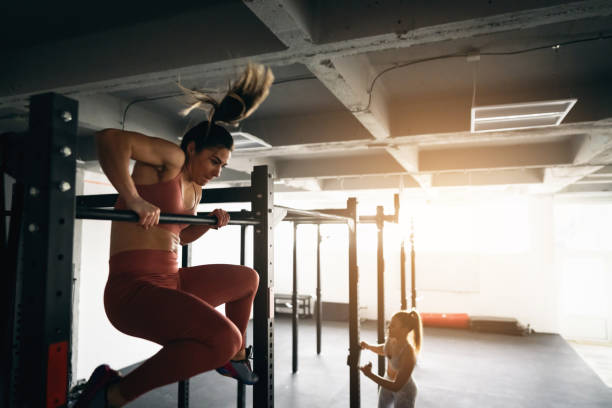 In the modern gym, on the bar, strong and flexible woman doing workout