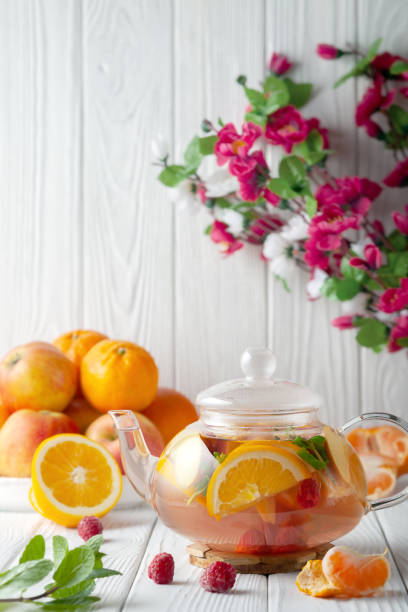 istock Fruit tea with berries, oranges and mint in a glass teapot on a white background 1359862829
