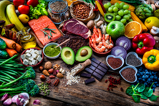 Food backgrounds: high angle view of a large group of raw healthy food that includes fruits, vegetables, raw salmon, beef meat, beans, legumes, tofu, flax seed, chia seed, berries, oat, nuts, moringa powder shot on rustic wooden table. High resolution 42Mp studio digital capture taken with SONY A7rII and Zeiss Batis 40mm F2.0 CF lens