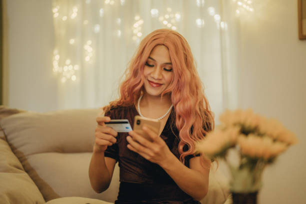 Happy LGBTQ online shopping with mobile phone. Asian LGBTQ shopping online on mobile phone with credit card on Christmas Day. thai transgender with mobile stock pictures, royalty-free photos & images