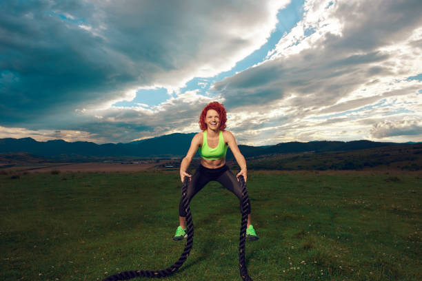 istock Enthusiast athlete woman on meadow training with battle rope. 1359867530