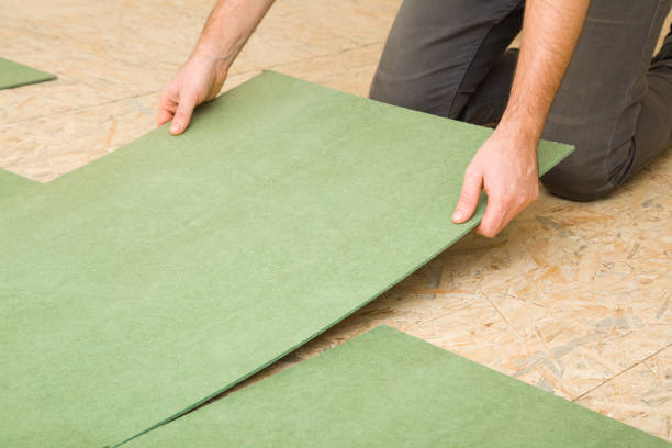Young adult man hands laying green natural wood fiber insulation board. Preparing surface from fibreboard underlay for laminate or parquet floor. Repair work of home. Renovation process. Closeup. stock photo