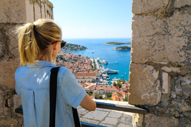 Blonde woman tourist enjoying view of Hvar harbor from Spanish fort stock photo
