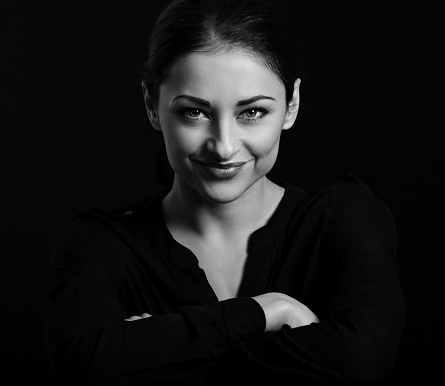 Beautiful confident happy smiling business woman with folded arms on black background with empty copy space. Closeup portrait of natural happiness.