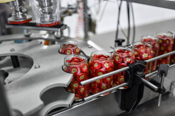 conserver à la machine les poivrons cerises farcis avec du fromage en mettant le couvercle sur les bocaux - usine agro alimentaire photos et images de collection