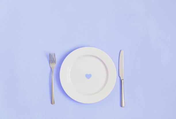 istock Festive romantic minimal table setting with a heart in a plate on a violet background. Love concept for Valentines day. Flat lay, copy space. 1359883315