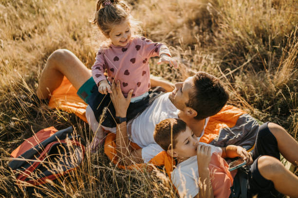 istock Young father lying on sleeping bag in nature with his two kids 1359884986