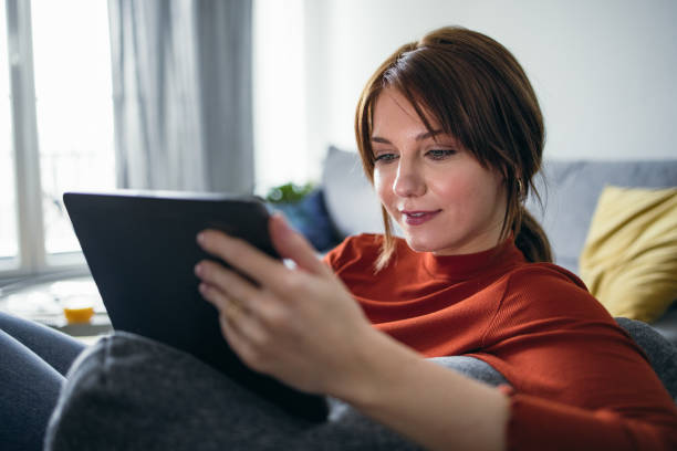 istock Student Life: Smiling Young Woman Using a Digital Tablet at Home 1359884994