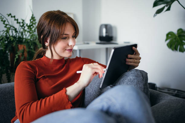 istock Student Life: Smiling Young Woman Using a Digital Tablet at Home 1359884995