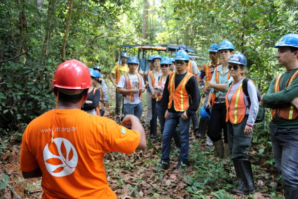 Group of people wearing safety gear listening to a guide in a forest during an outdoor training or tour.
