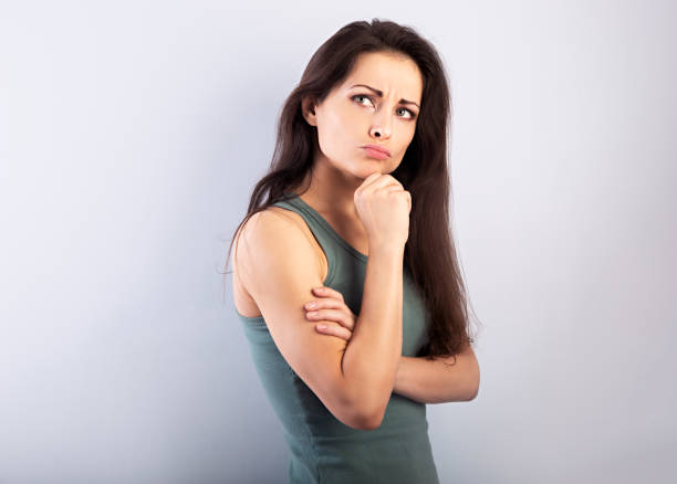 istock Beautiful serious angry thinking young woman looking up on empty blue studio 1359894368