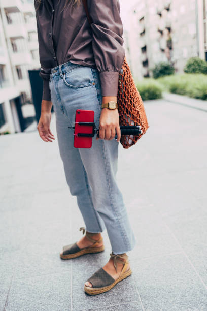 An Unrecognizable Woman Taking A Stroll While Holding Her Red Smartphone On A Selfie Stick