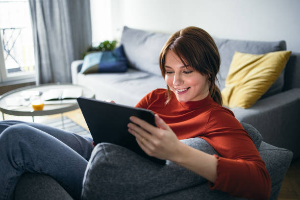 istock Student Life: Smiling Young Woman Using a Digital Tablet at Home 1359898201