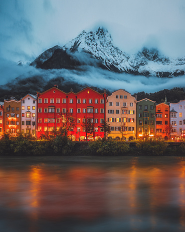 Colorful cityscape of Innsbruck at the Mariahilf district with the snowy and foggy Nordkette mountain chain and Inn river in Austria