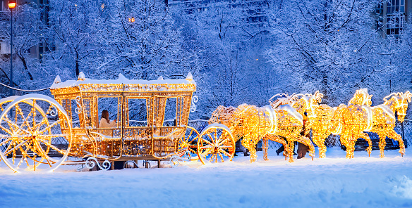 MOSCOW, RUSSIA-DECEMBERY 14TH 2021: young woman making a selfie sitting  in golden horse-drawn carriage. Christmas and happy new year mood.