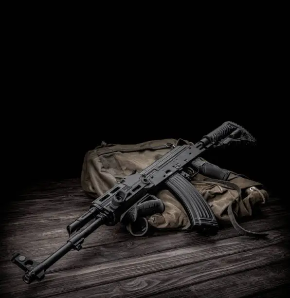 Photo of Soviet carbine in modern body kit. Weapons of Russia and the Soviet Union. Classic Soviet AK machine gun on a wooden background.