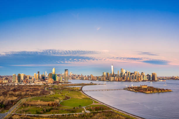 Aerial view of New York City and Jersey City skylines Aerial view of New York City and Jersey City skylines together with Ellis Island, as viewed from above Liberty State Park, in New Jersey, at dusk. jersey city stock pictures, royalty-free photos & images