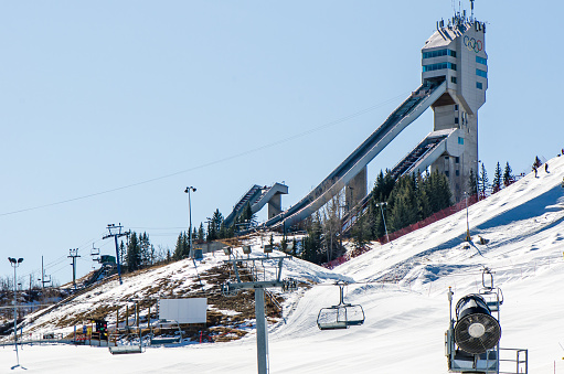 Calgary, Alberta, Canada, March 18, 2021: Olympic ski jumping venue set up, ski lift and a snowmaking machine at the Olympic Park.