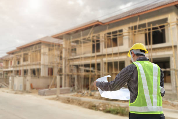 istock young professional engineer in protective helmet and blueprints paper at the house building construction site 1359907231