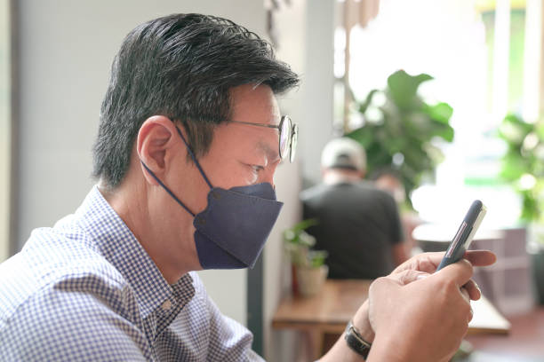 istock Man with face mask on using his phone in a restaurant 1359908397