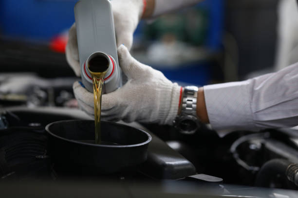 istock Worker refueling and pouring new oil into engine motor car 1359908514