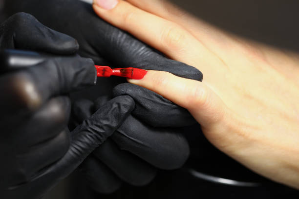 istock Professional salon worker cover clients nails with red colour polish 1359908587