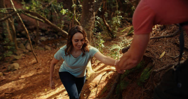 istock Shot of a man helping his partner to higher ground while out exploring a forest together 1359913732