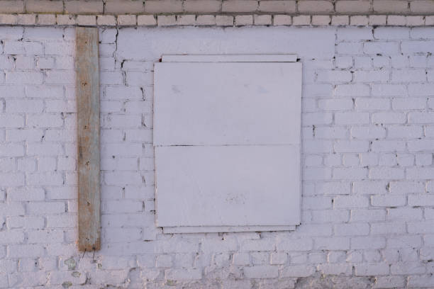 istock Brick building with a window covered with an iron panel. Evacuation and abandoned house. Old background. 1359924499