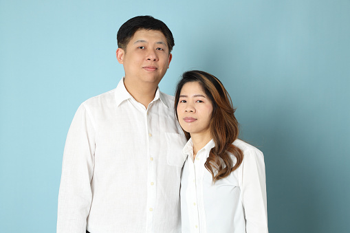 The Asian couple with white shirt standing on the blue background.
