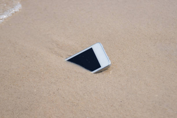 White Mobile phone on sand at beach concept electronic waste\