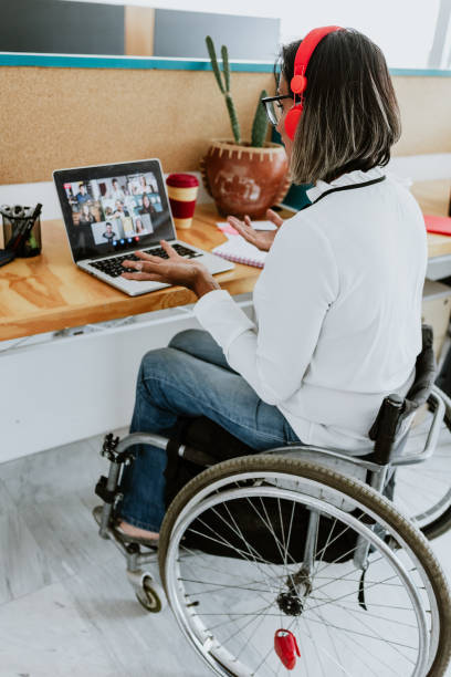 transgender latin woman on wheelchair on video call working with computer at the office in Mexico Latin America transgender latin woman on wheelchair on video call working with computer at the office in Mexico Latin America transgender person in office stock pictures, royalty-free photos & images