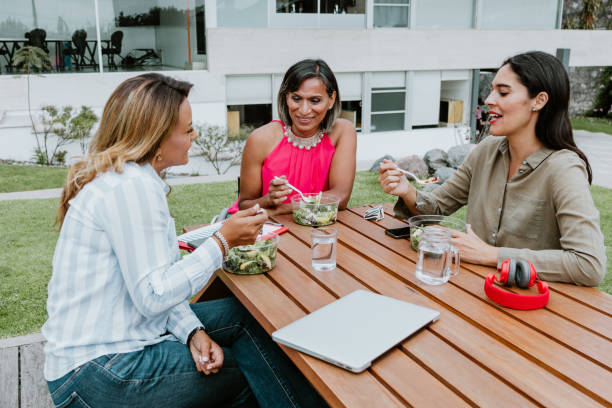 transgender latin business woman middle age and colleagues eating salad at the office terrace in Mexico Latin America transgender latin business woman middle age and colleagues eating salad at the office terrace in Mexico Latin America transgender person in office stock pictures, royalty-free photos & images