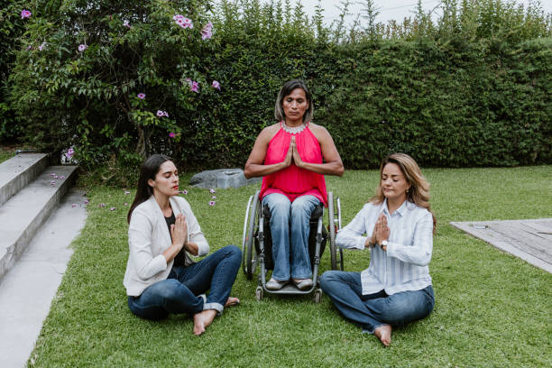 latin business frau transgender auf rädern stuhl und freunde sitzen auf gras und meditieren auf terrasse büro in mexiko lateinamerika - zen like meditating yoga business stock-fotos und bilder